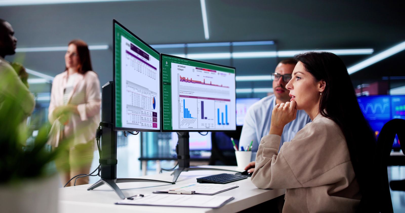 A planning team reviewing dashboards on two monitors