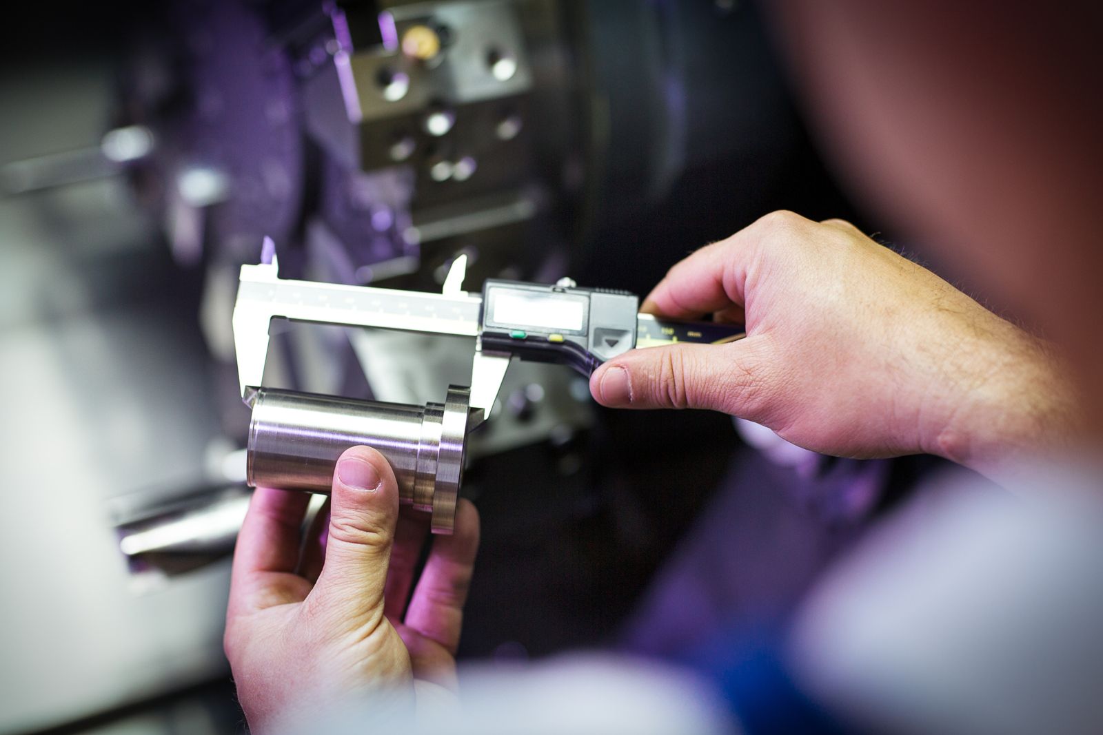 A machinist measuring a turned part with a micrometer