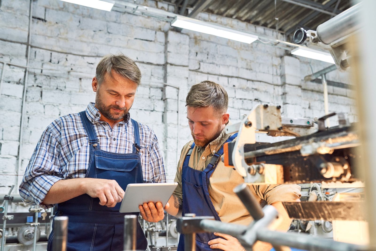 Two machinists reviewing a job on a tablet at the machine